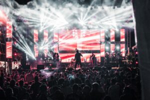 Energetic live music concert featuring performers on a vibrant stage, captivating a large audience.